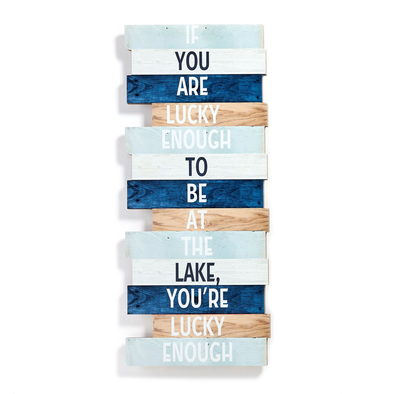 23Inch Rectangular Wooden Wall Sign Features Print Typography In Alternating Blue, White And Beige Colorways On A Natural Wood Background With The Message "If You Are Lucky Enough To Be At The Lake, You're Lucky Enough."